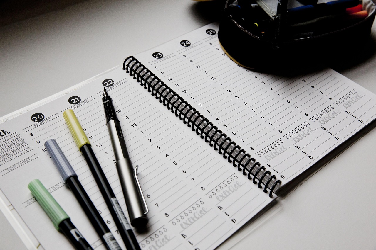 Agenda de planning hebdomadaire ouvert avec des stylos