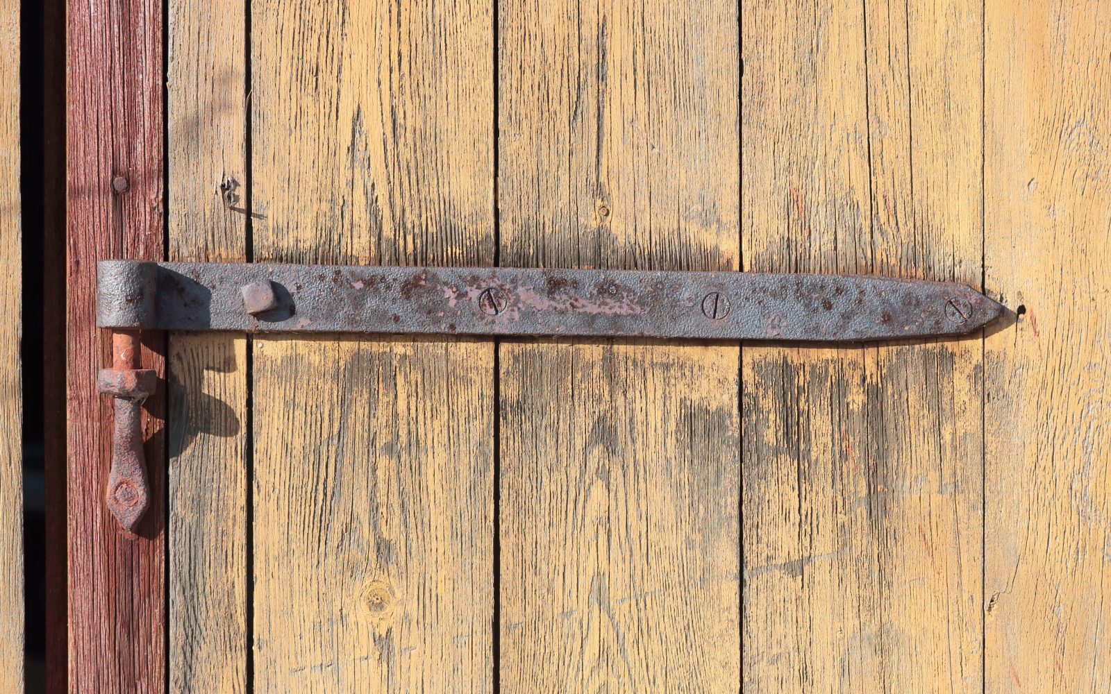 Charnière rouillée fixée sur une porte en bois