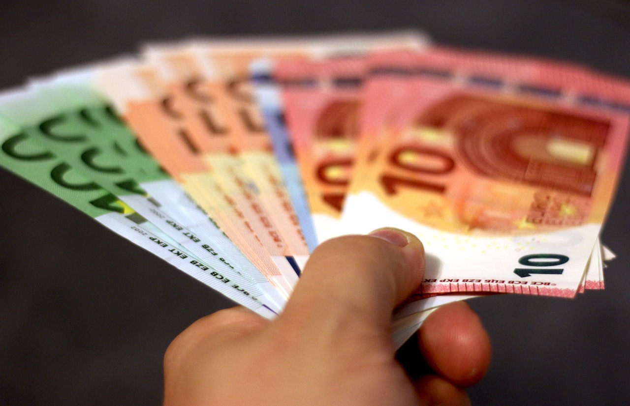 Éventail de billets en euros tenus dans une main