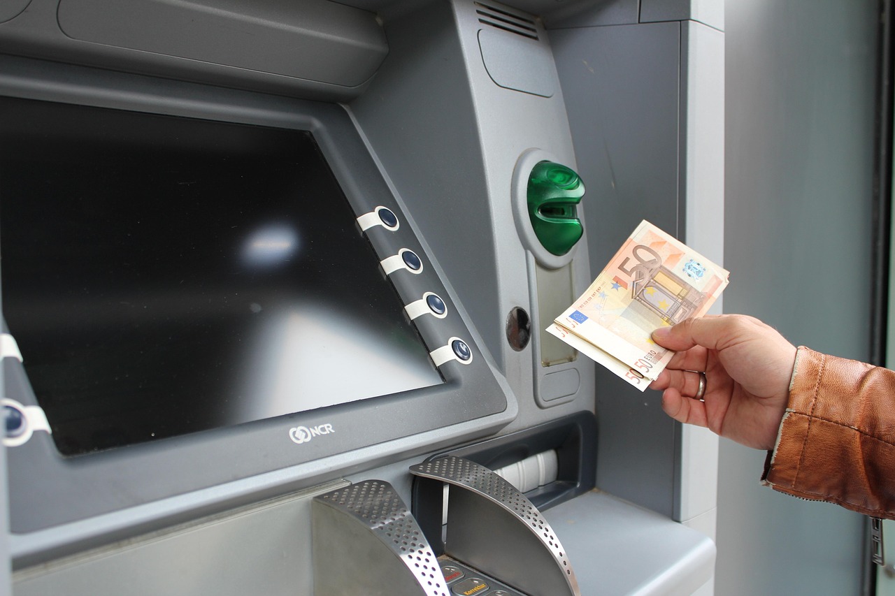 Main qui retire des billets de 50 euros à un distributeur automatique de billets