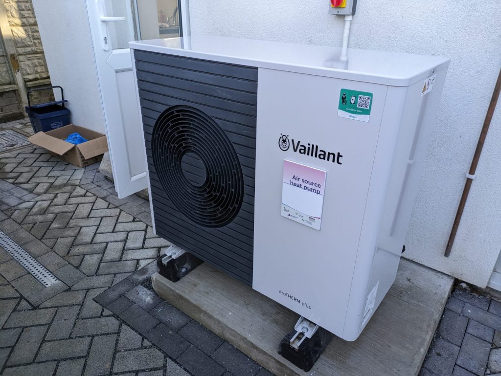 Unité extérieure d'une pompe à chaleur air/eau installée contre le mur d'une maison