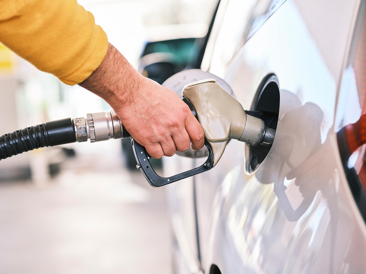 Main qui tient le pistolet de carburant lors d'un plein à la station-service