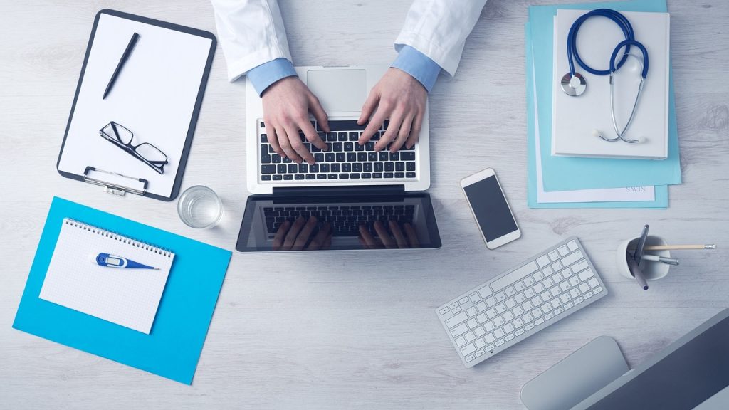 Bureau avec ordinateur portable, stéthoscope et lunettes pour une téléconsultation