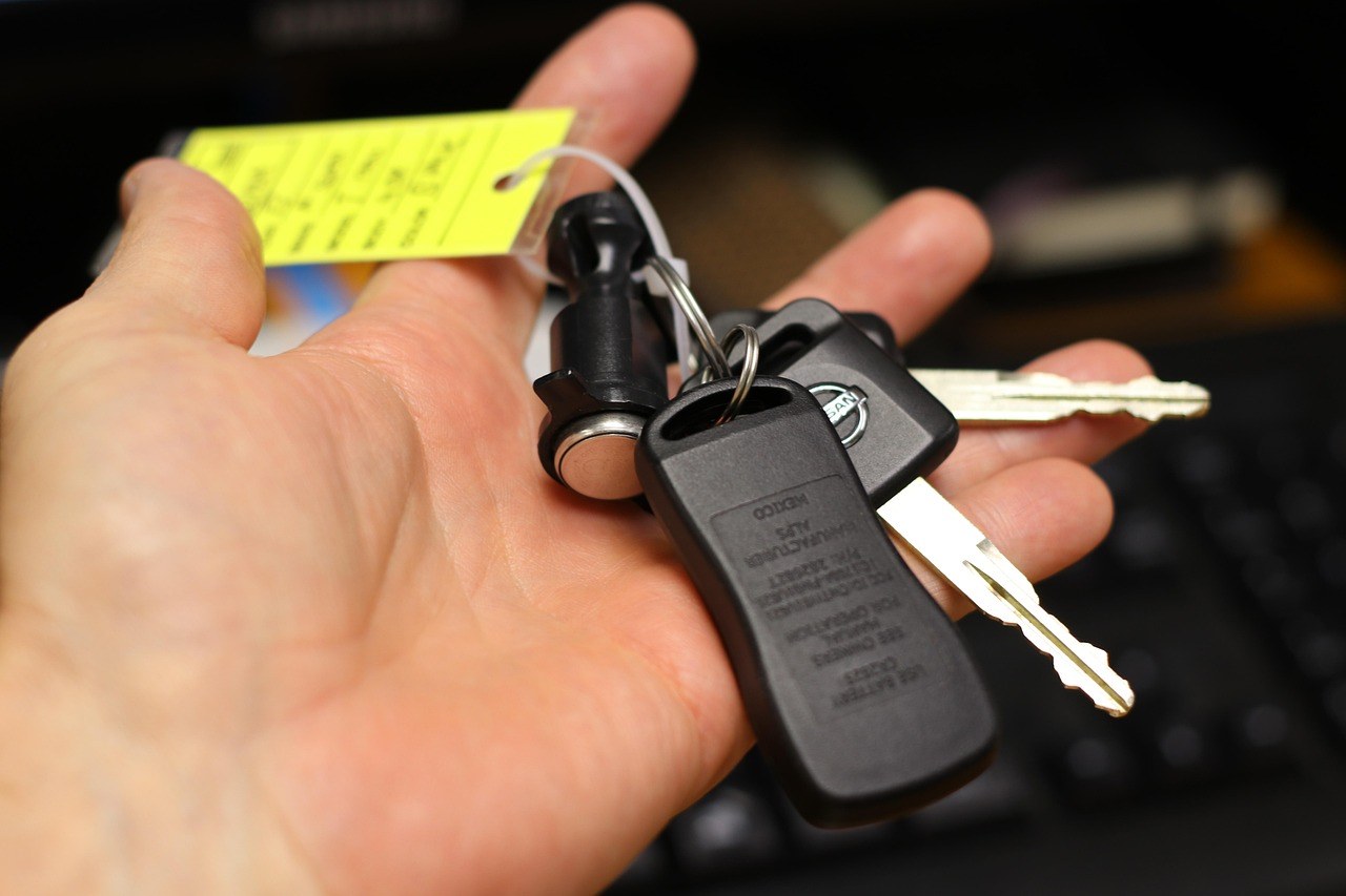 Main tenant un trousseau de cles de voiture avec une etiquette de vente jaune attachee