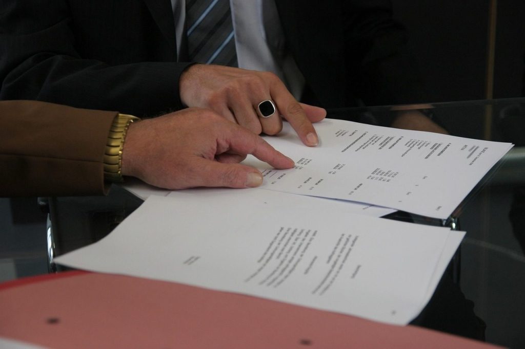 Main qui signe un contrat de vente, gros plan sur le document et le stylo