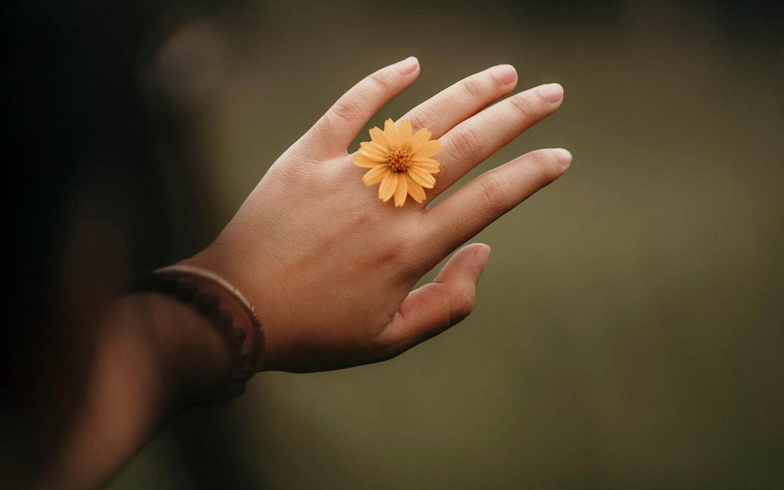 Main portant une bague avec une fleur, gros plan sur le bijou